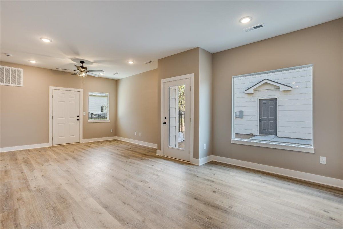An empty living room with hardwood floors and a ceiling fan.