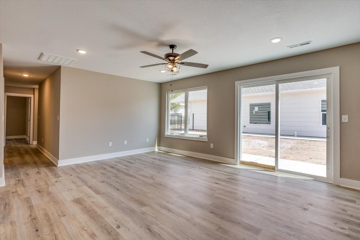 An empty living room with hardwood floors and a ceiling fan.