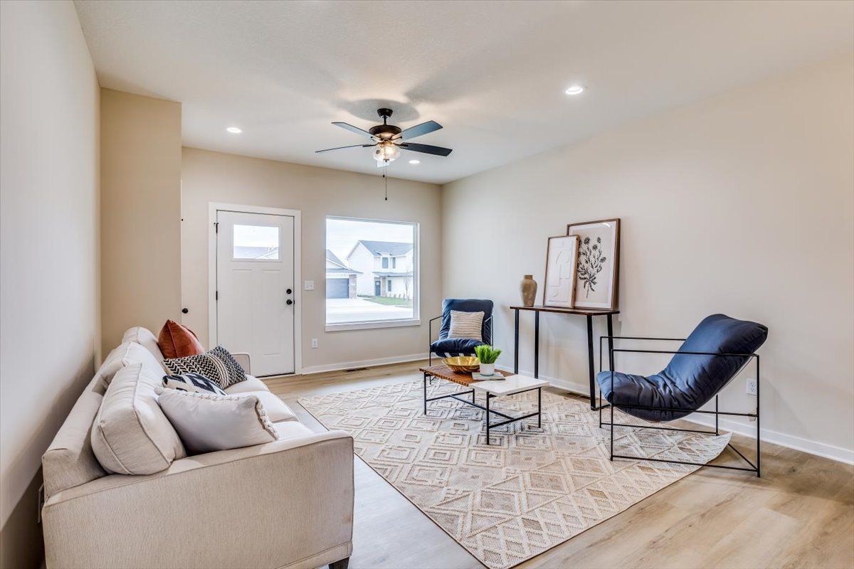 A living room with a couch , chair , coffee table and ceiling fan.
