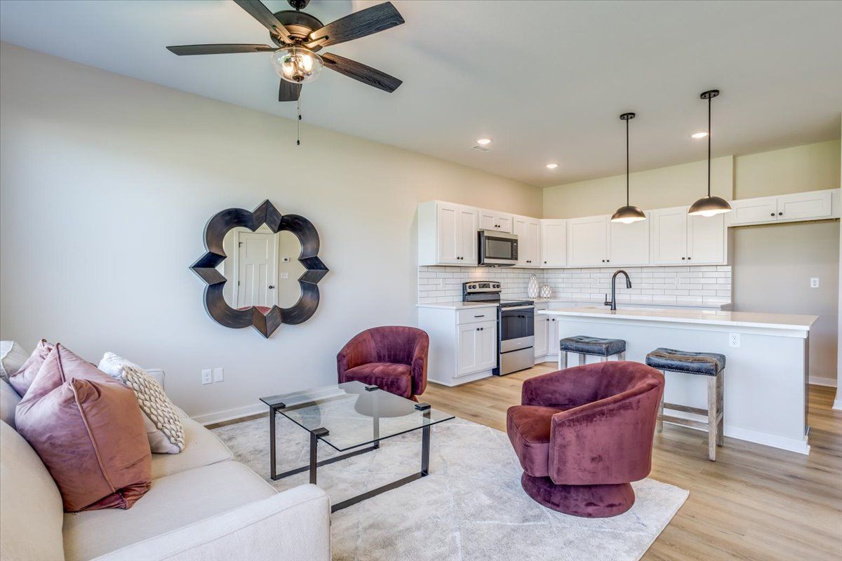 A living room with a couch , chairs , a coffee table and a ceiling fan.