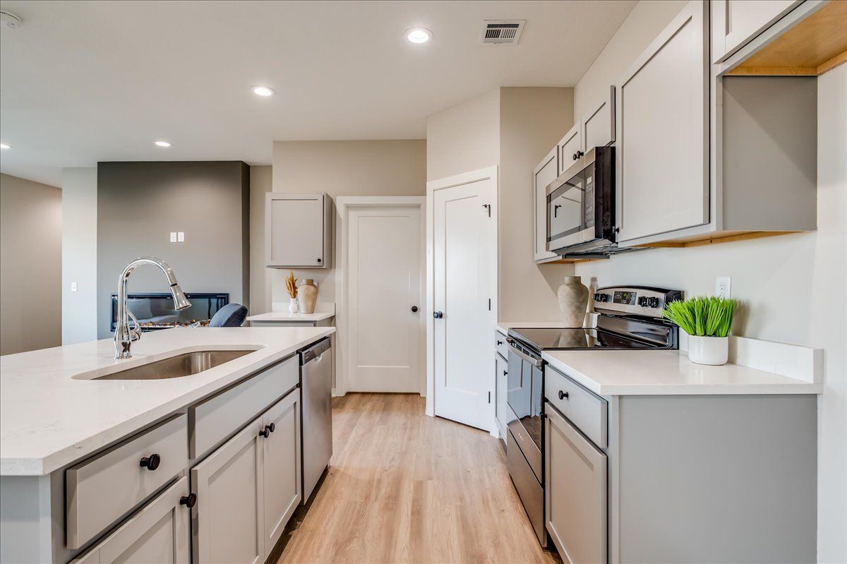 A kitchen with white cabinets , stainless steel appliances , a sink , and a microwave.