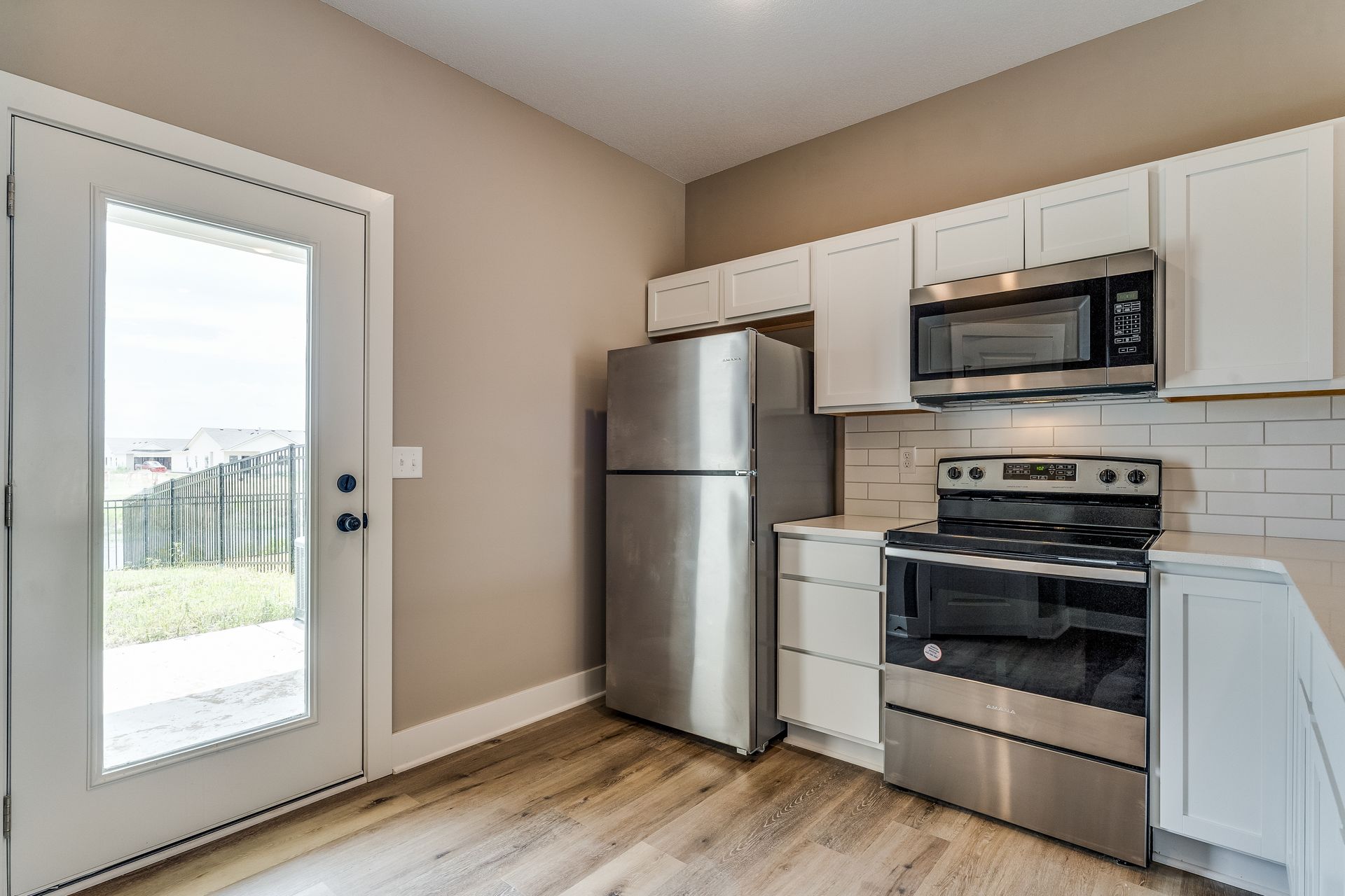 A kitchen with stainless steel appliances , a refrigerator , stove and microwave.