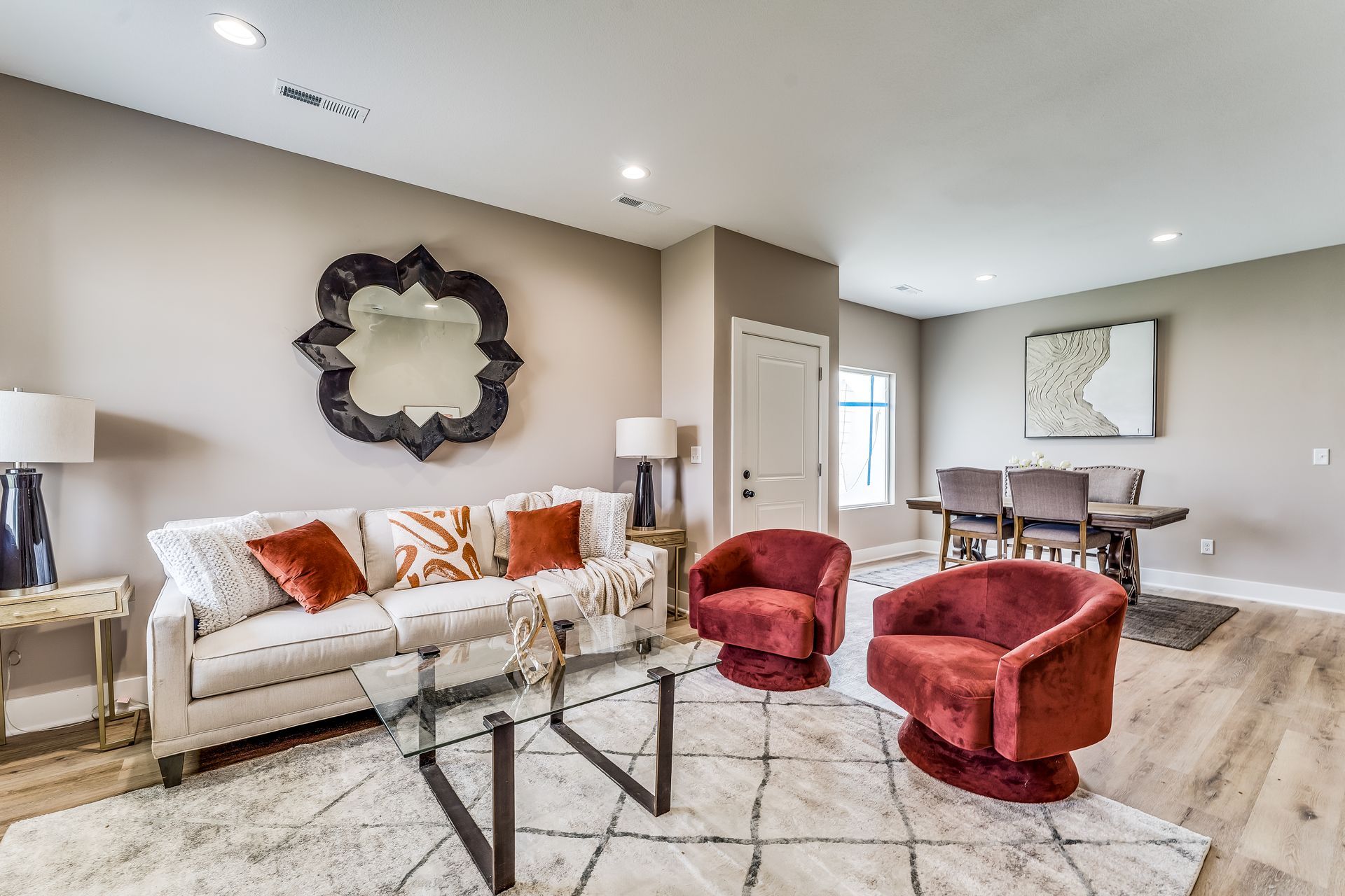 A living room with a couch , chairs , a table and a mirror.