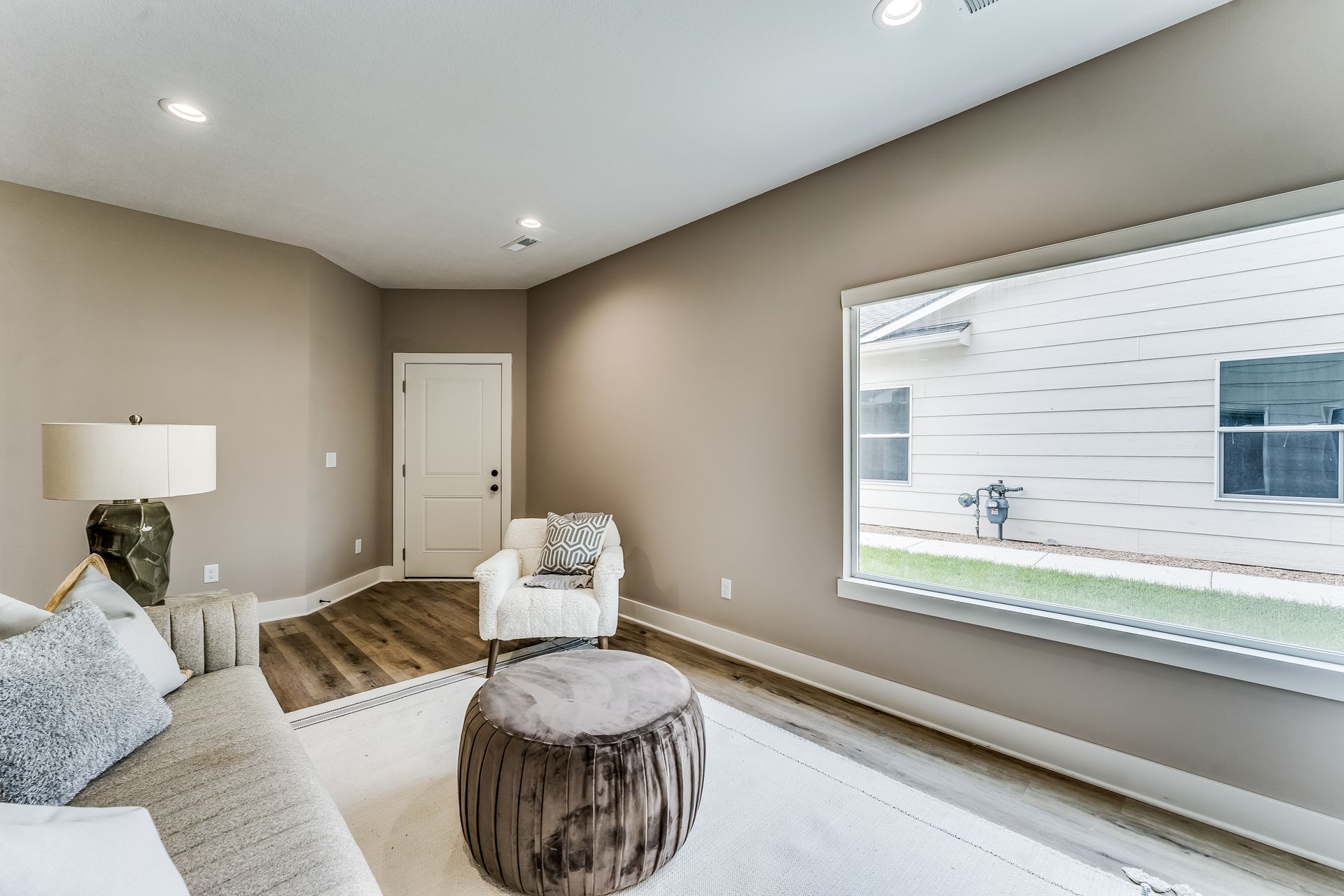 A living room with a couch , chair , table and large window.