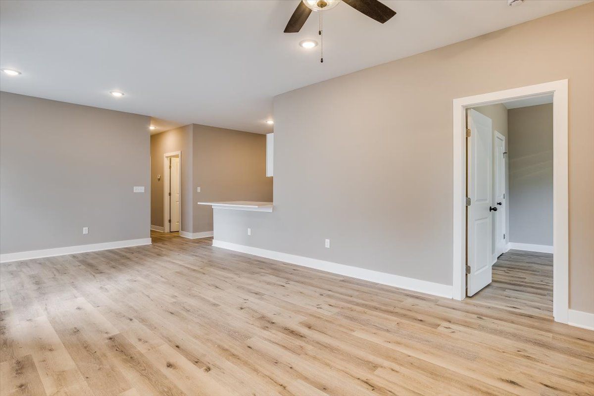 An empty living room with hardwood floors and a ceiling fan.