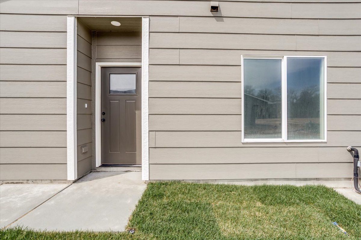 The front door of a house with a window and a concrete walkway leading to it.
