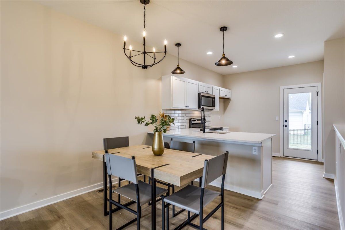 A dining room table and chairs in a kitchen with a chandelier hanging from the ceiling.