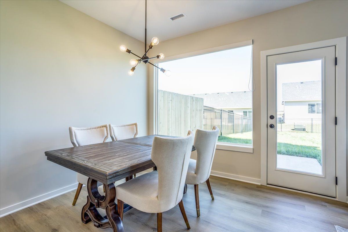 A dining room with a table and chairs and a large window.