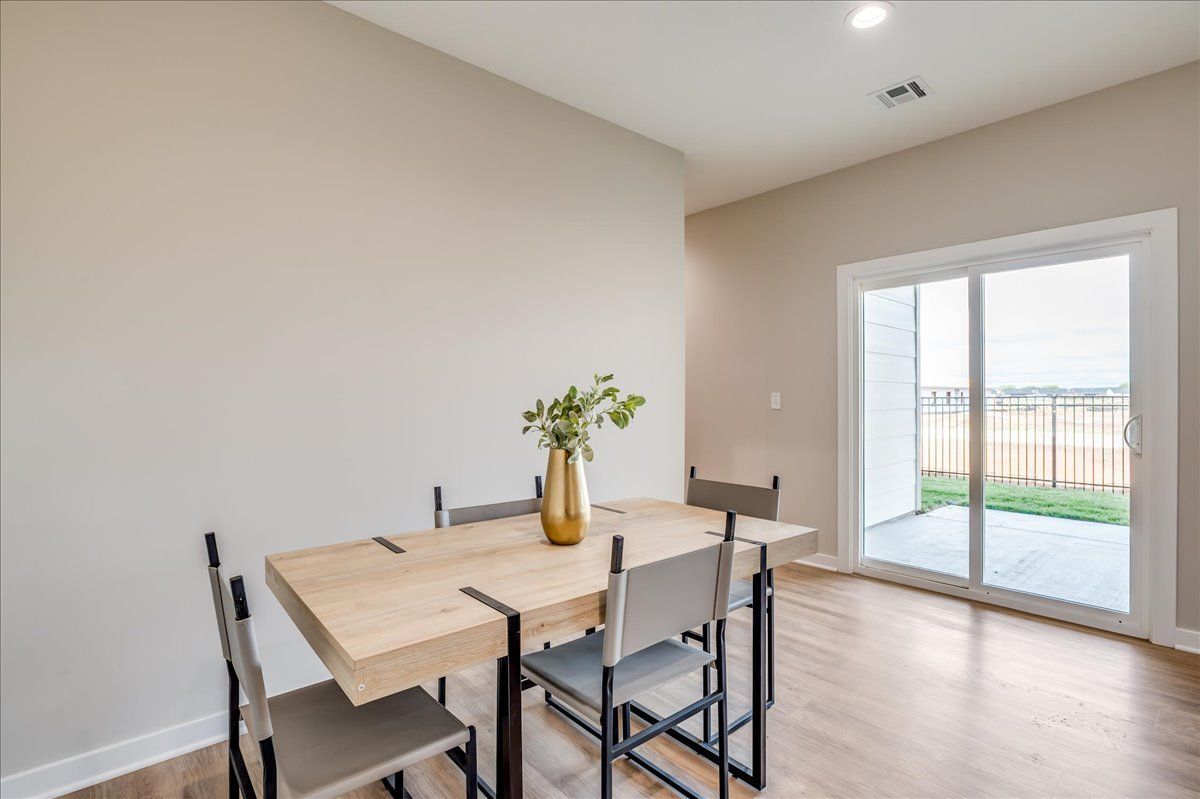 A dining room with a table and chairs and a vase on the table.