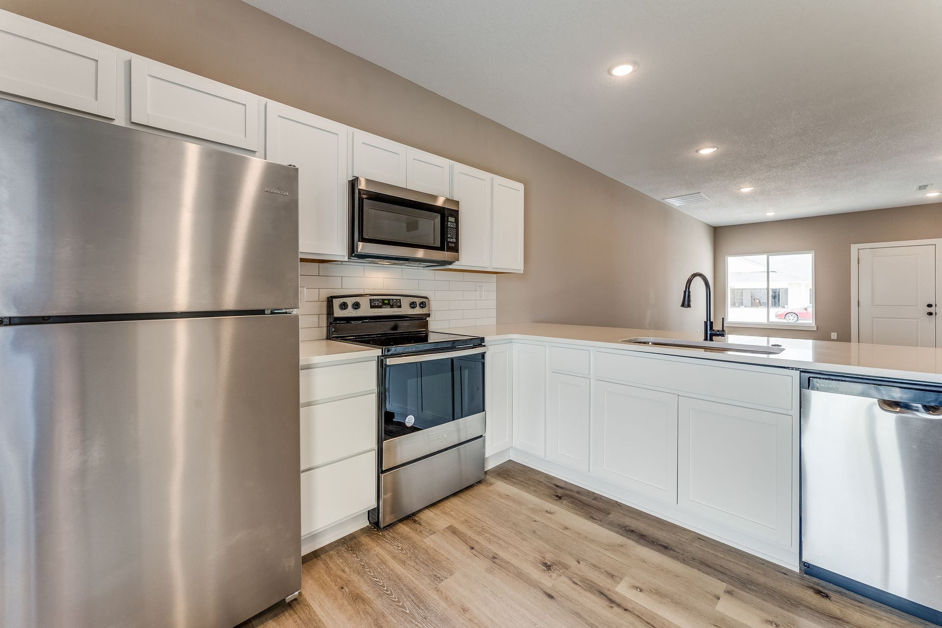A kitchen with stainless steel appliances and white cabinets.