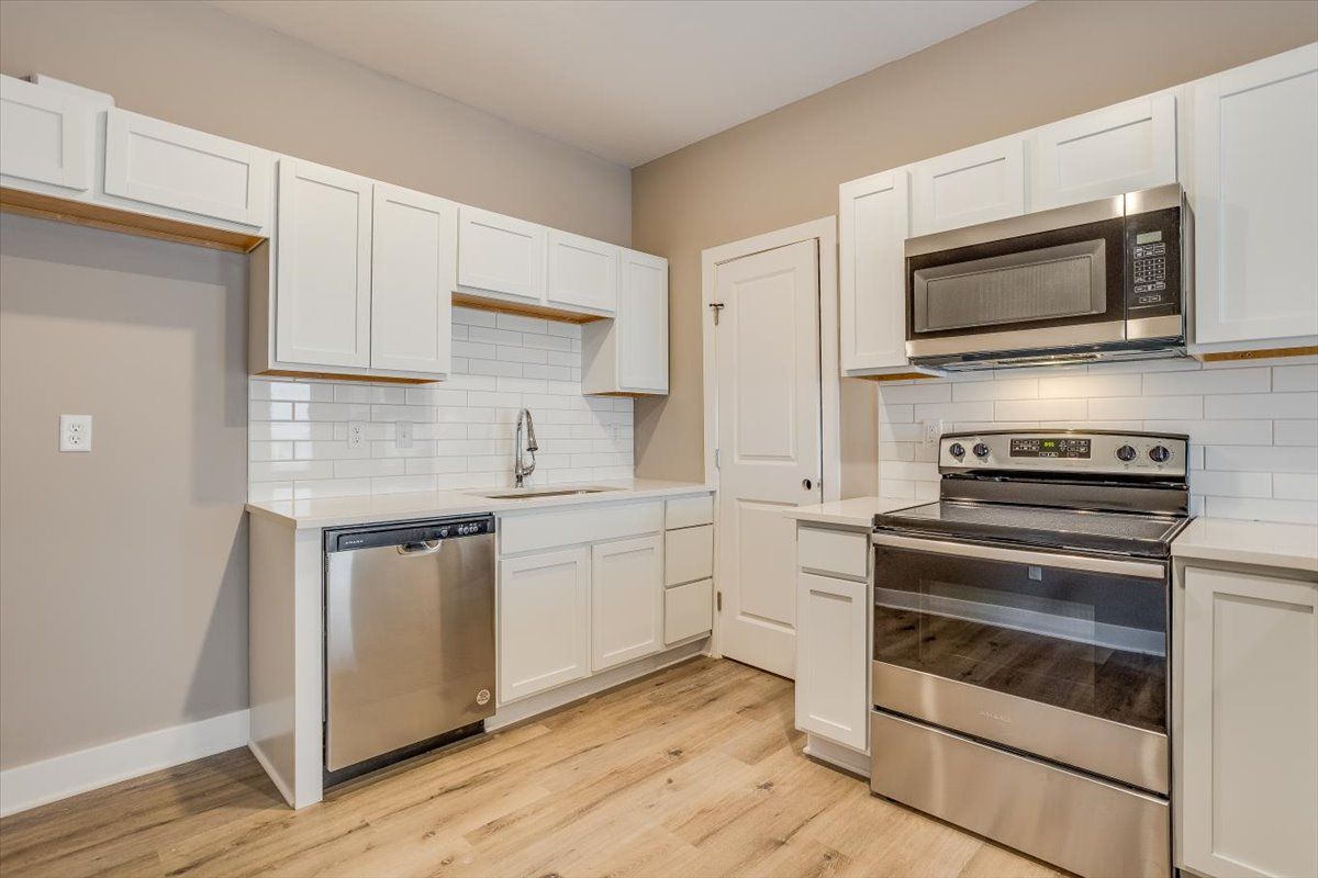 A kitchen with stainless steel appliances and white cabinets.