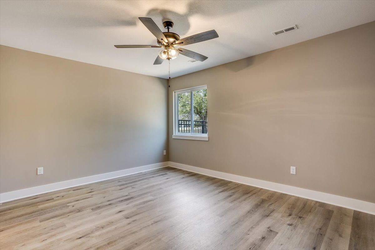 An empty bedroom with a ceiling fan and a window.