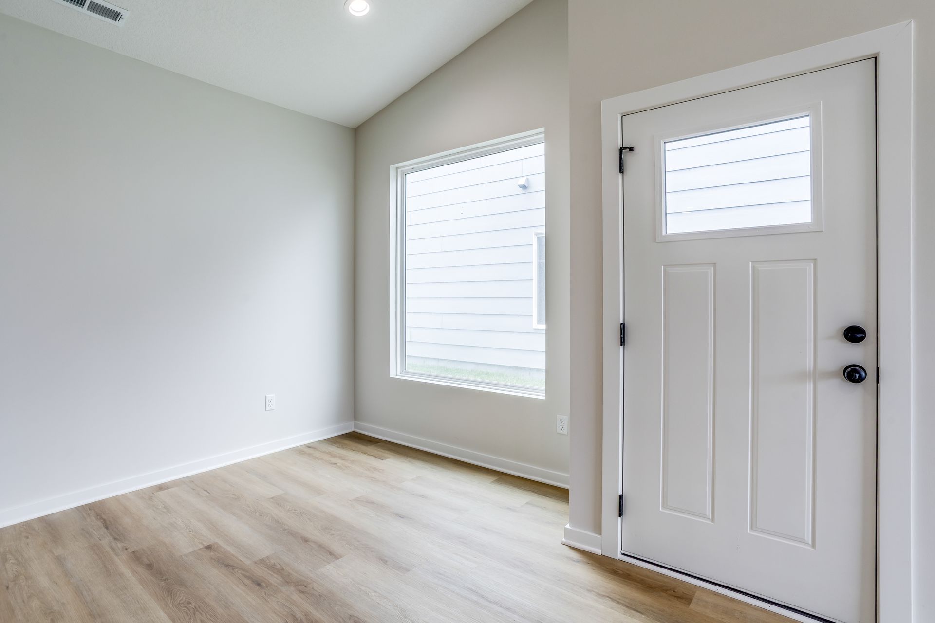 An empty room with a white door and a window.