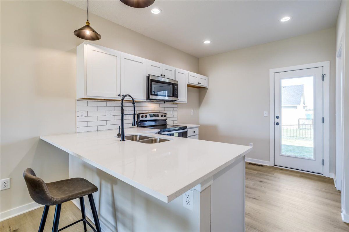 A kitchen with a sink , stove , microwave and stools.