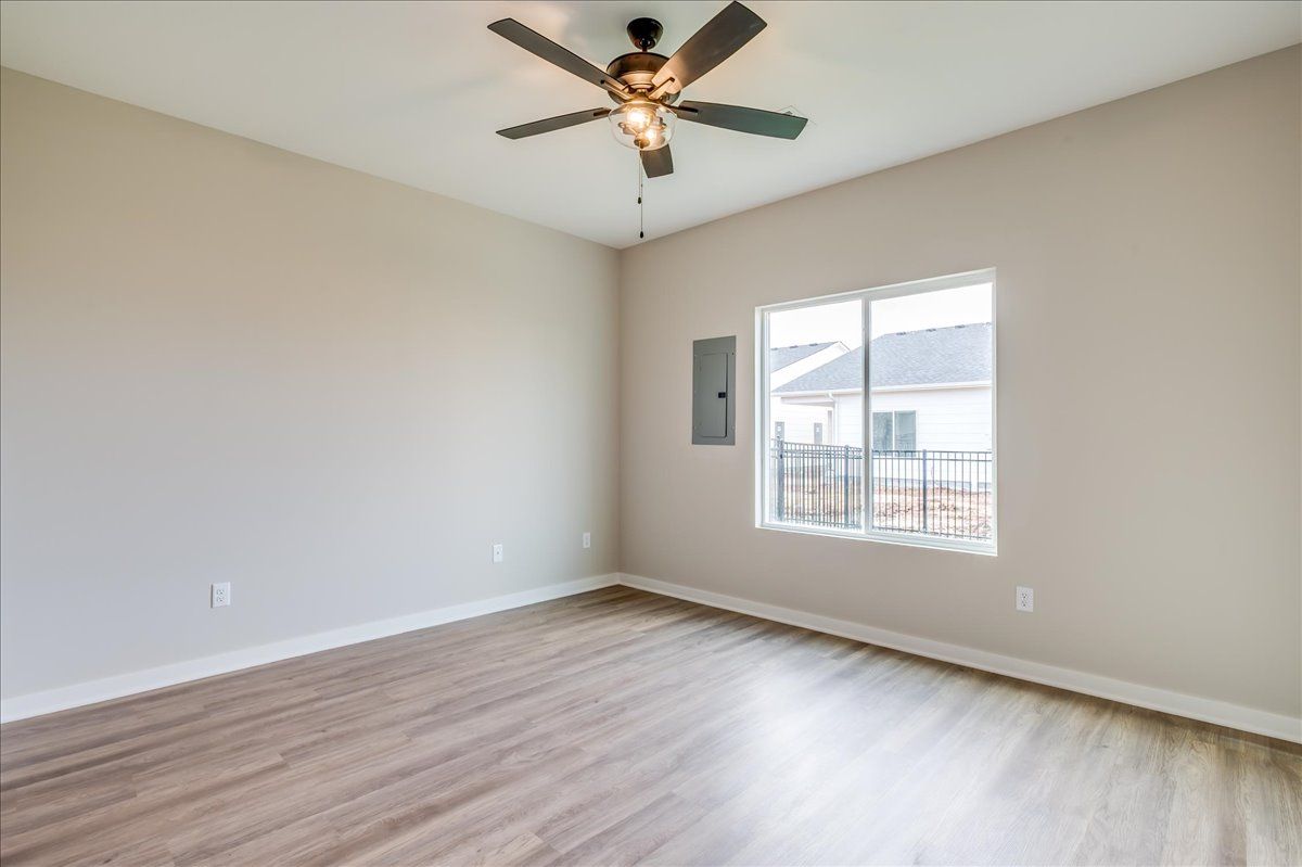 An empty room with a ceiling fan and a window.