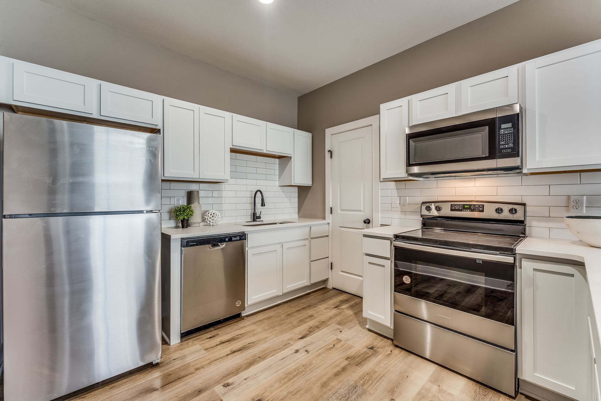 A kitchen with stainless steel appliances and white cabinets.
