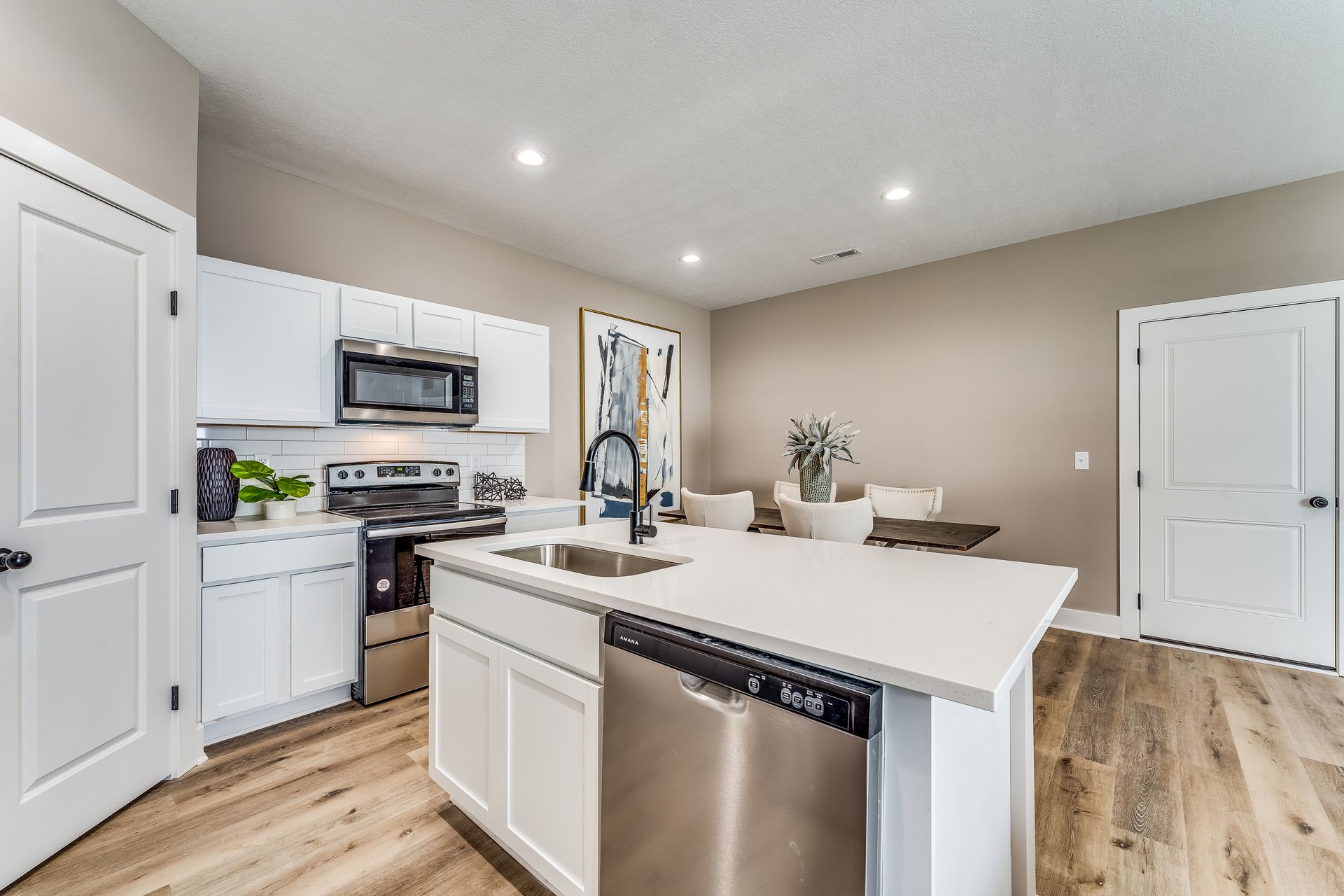 A kitchen with white cabinets , stainless steel appliances , and a large island.