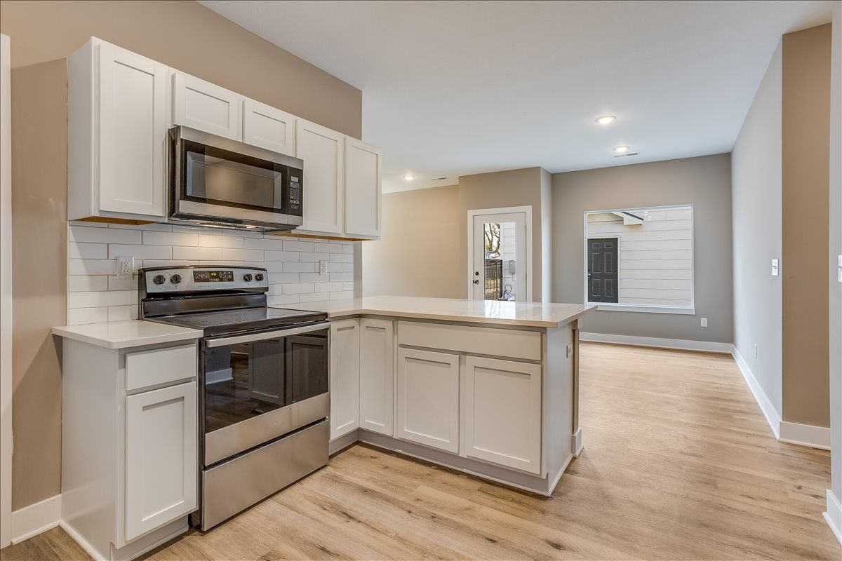 A kitchen with stainless steel appliances and white cabinets.