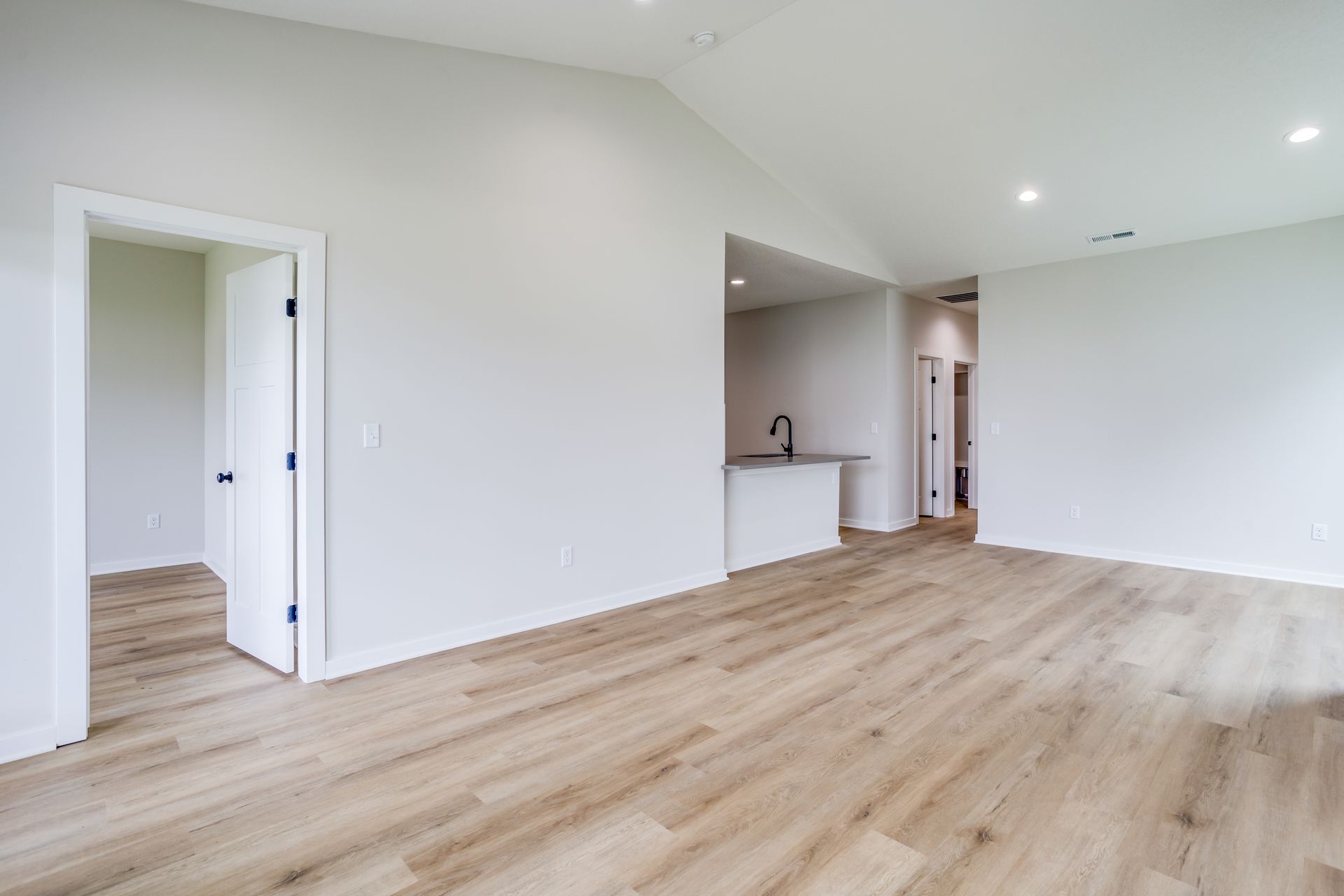 An empty living room with hardwood floors and white walls.