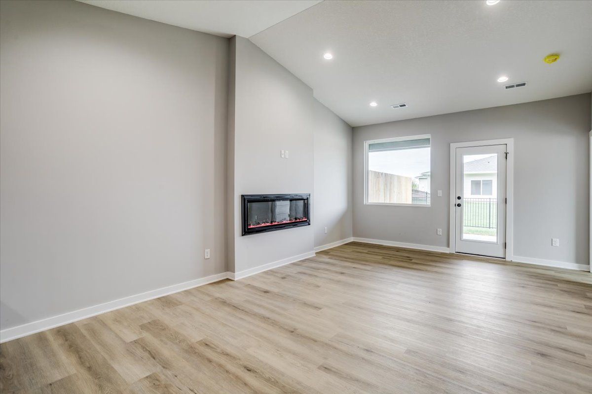 An empty living room with hardwood floors and a fireplace.