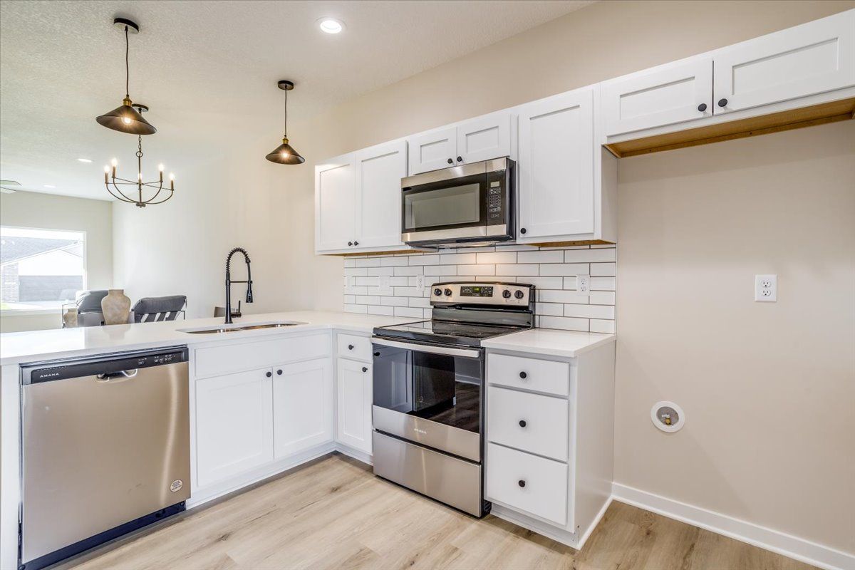 A kitchen with white cabinets and stainless steel appliances.