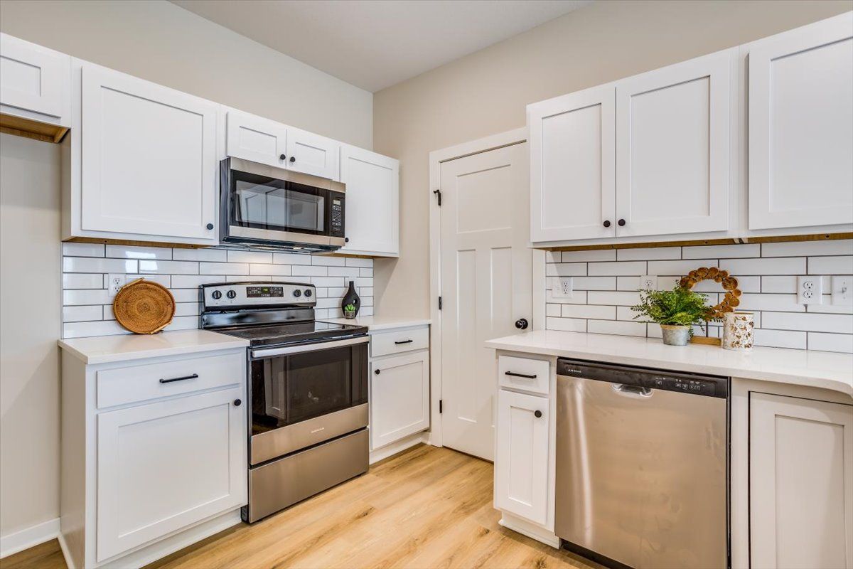 A kitchen with white cabinets and stainless steel appliances.