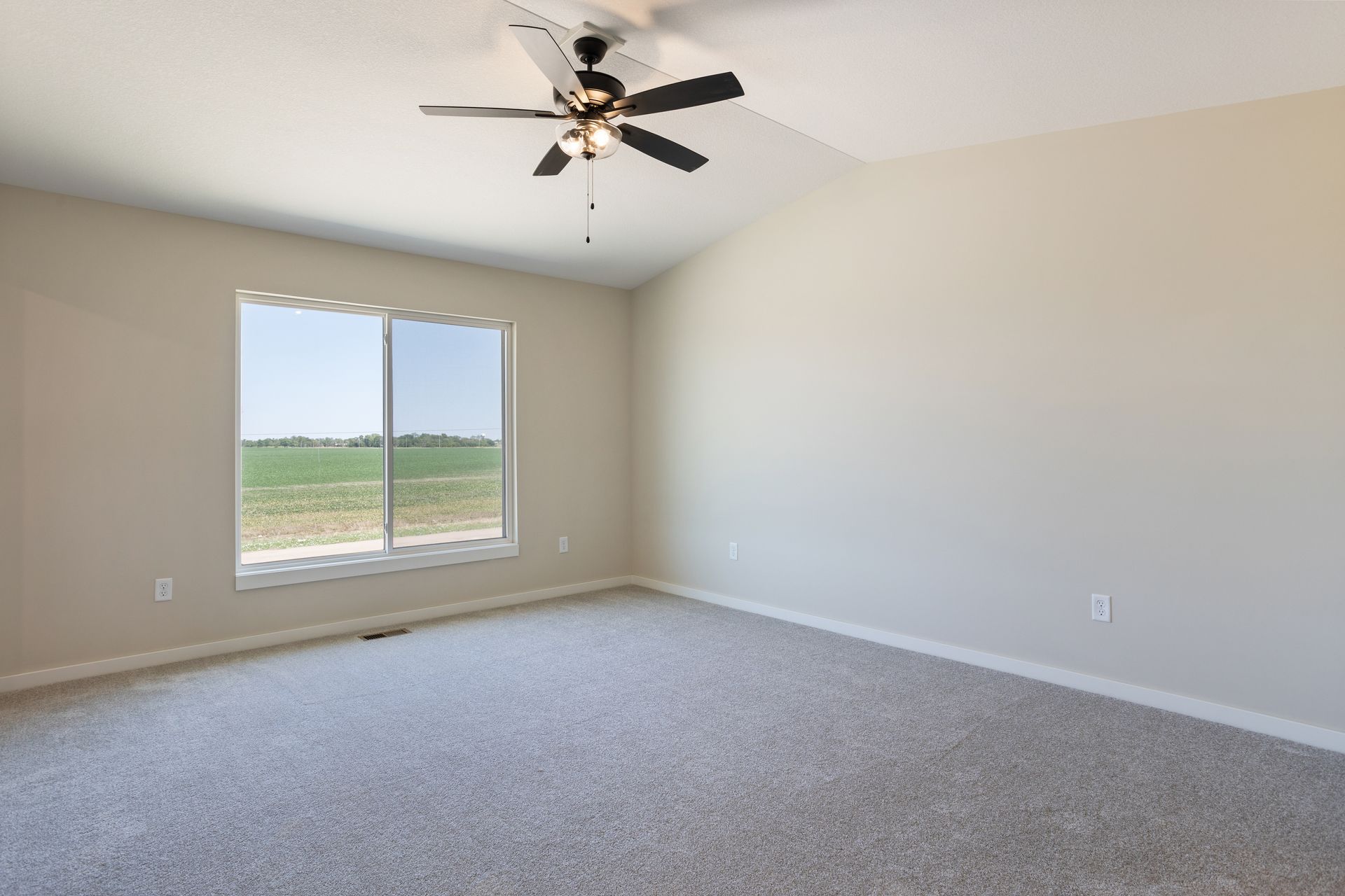 An empty bedroom with a ceiling fan and a window.