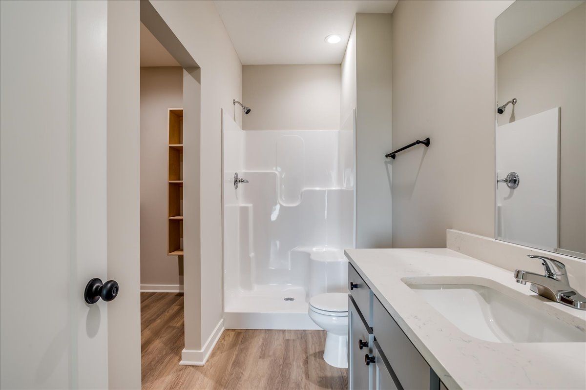 A bathroom with a toilet , sink and shower.