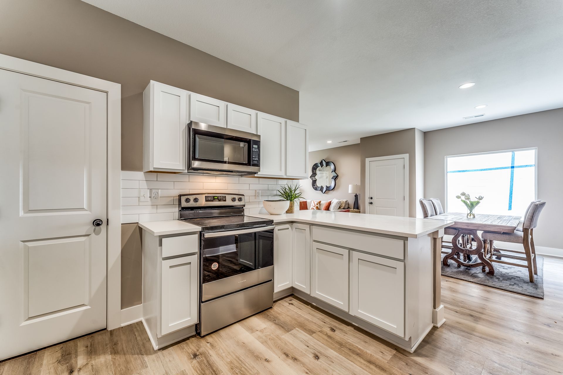 A kitchen with white cabinets , stainless steel appliances , and hardwood floors.