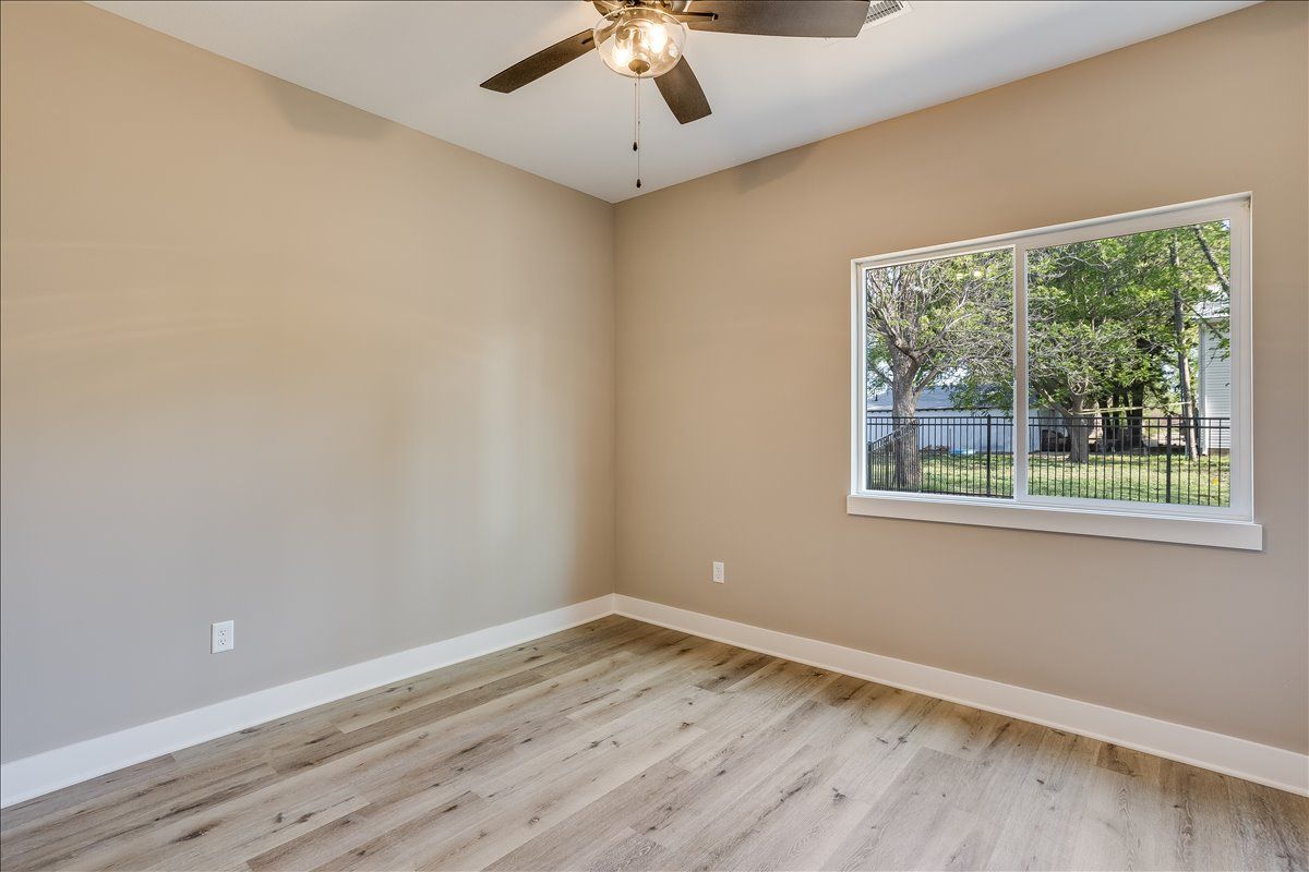 An empty room with a ceiling fan and a window.