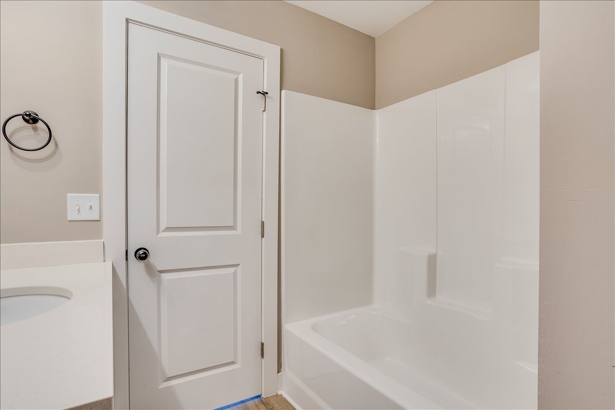 A bathroom with a bathtub , sink , and door.
