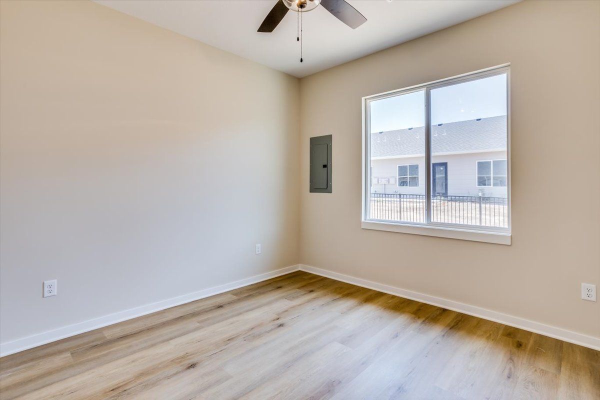 An empty room with a large window and a ceiling fan.
