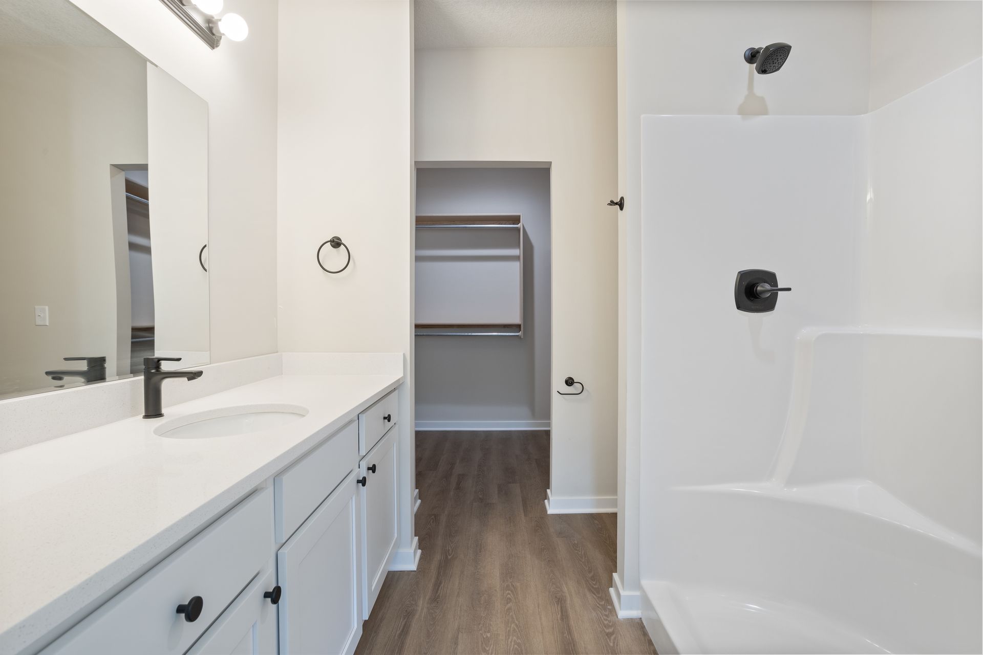A bathroom with two sinks , a tub , and a walk in closet.