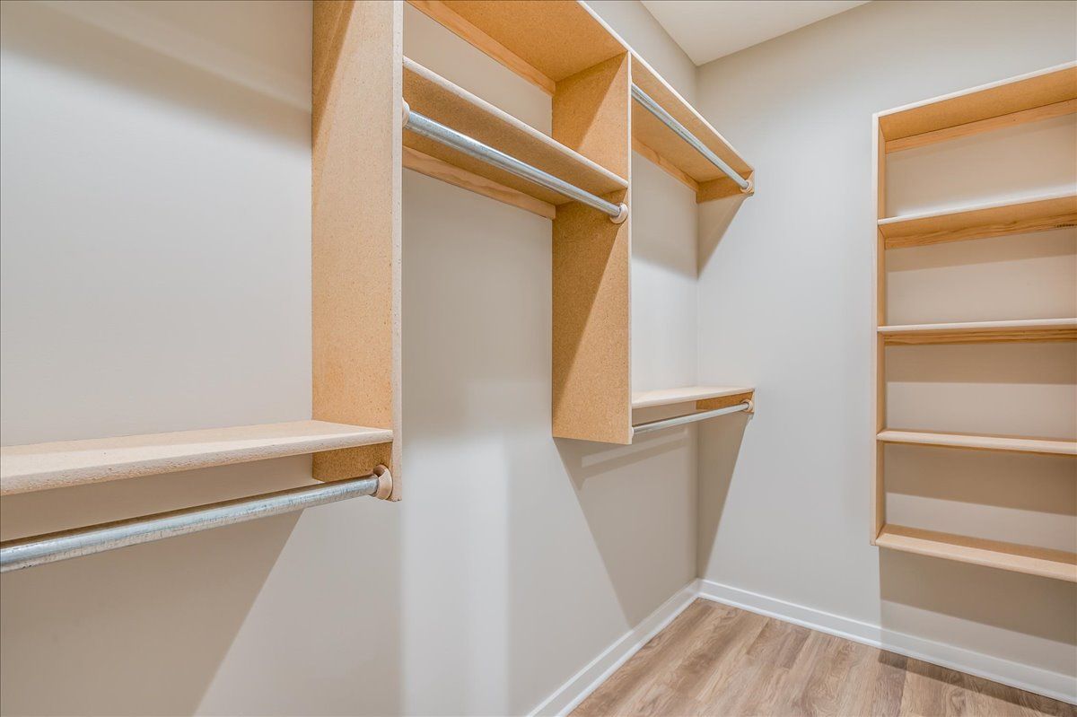 A walk in closet with wooden shelves and clothes racks.