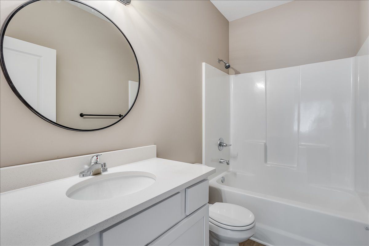 A bathroom with a sink , toilet , tub and mirror.