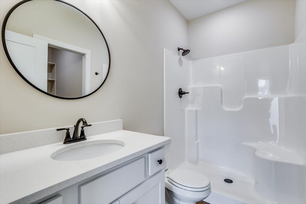 A bathroom with a sink , toilet , shower and mirror.
