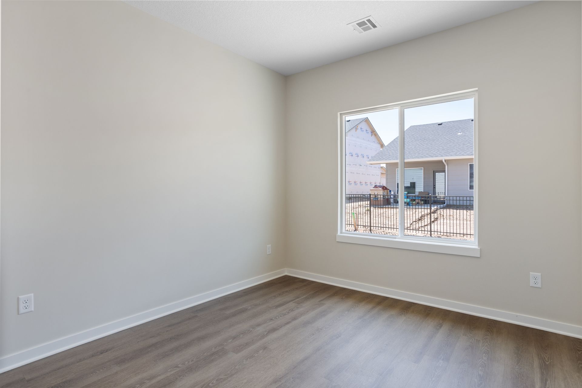 An empty room with hardwood floors and a large window.