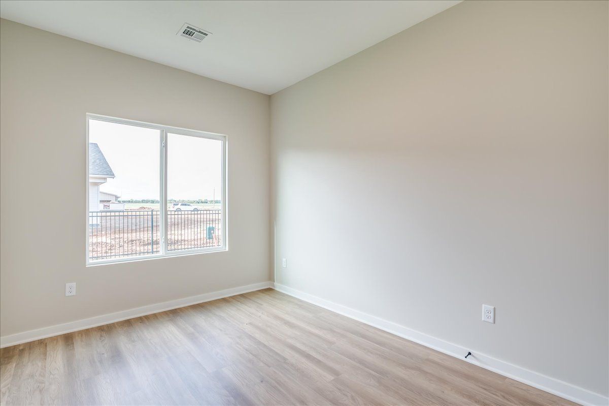 An empty room with hardwood floors and two windows.