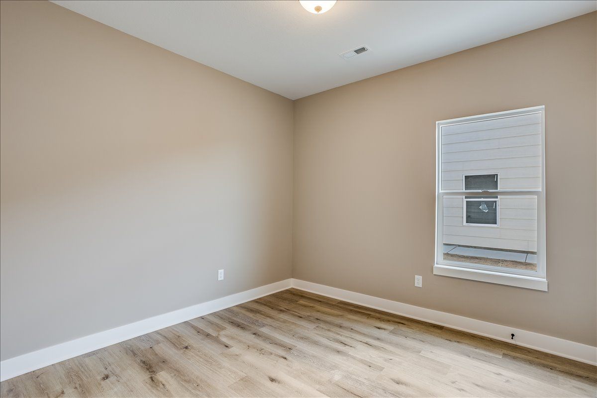 An empty room with hardwood floors and a window.