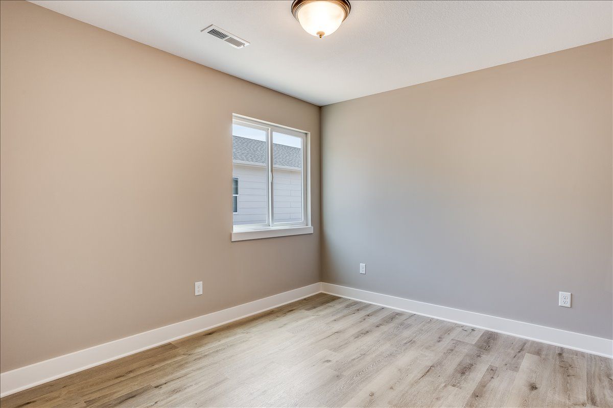 An empty bedroom with hardwood floors and a window.