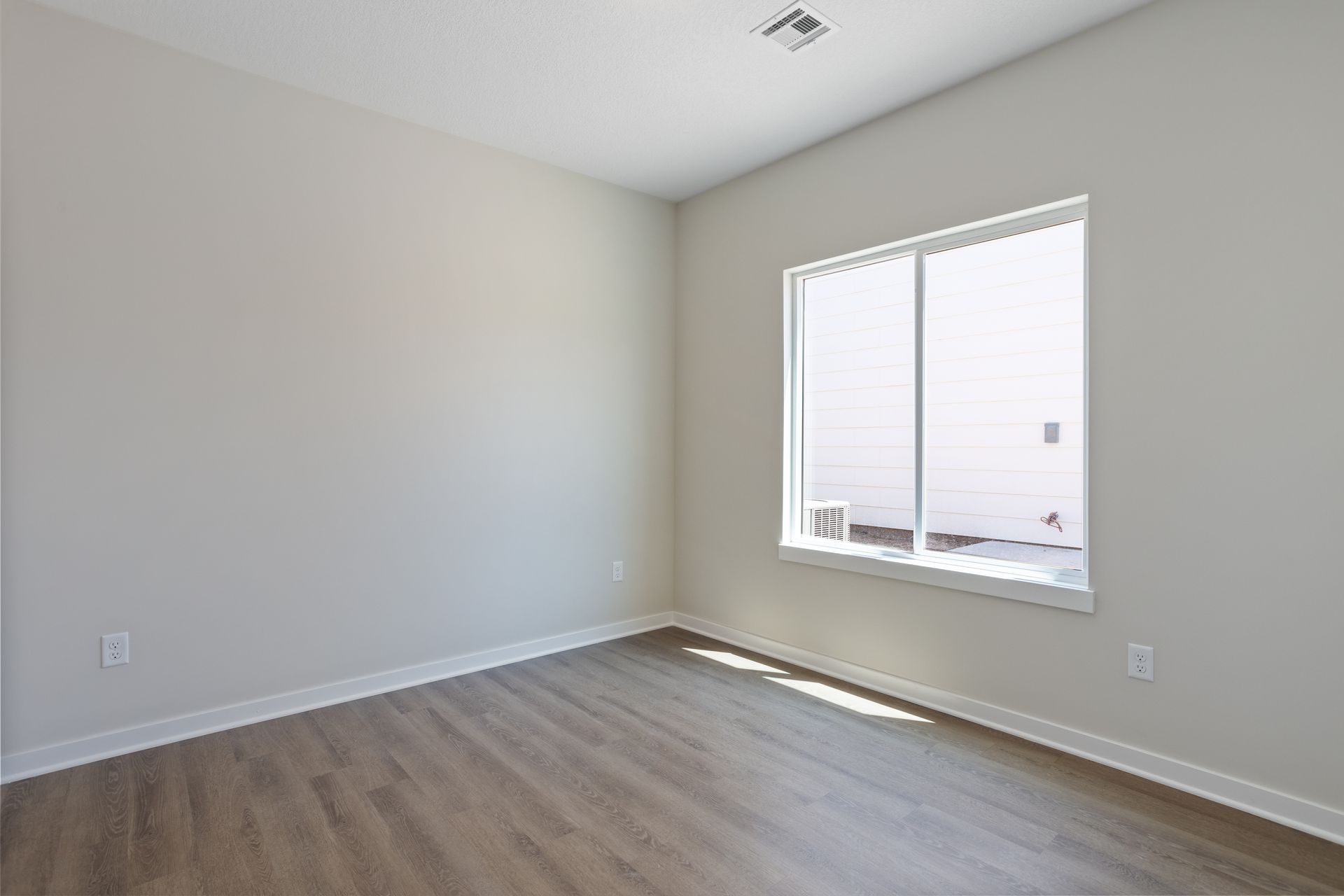 An empty room with hardwood floors and a large window.