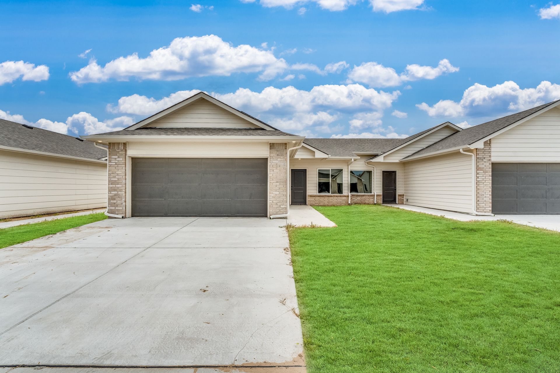 The front of a house with two garages and a lush green lawn.