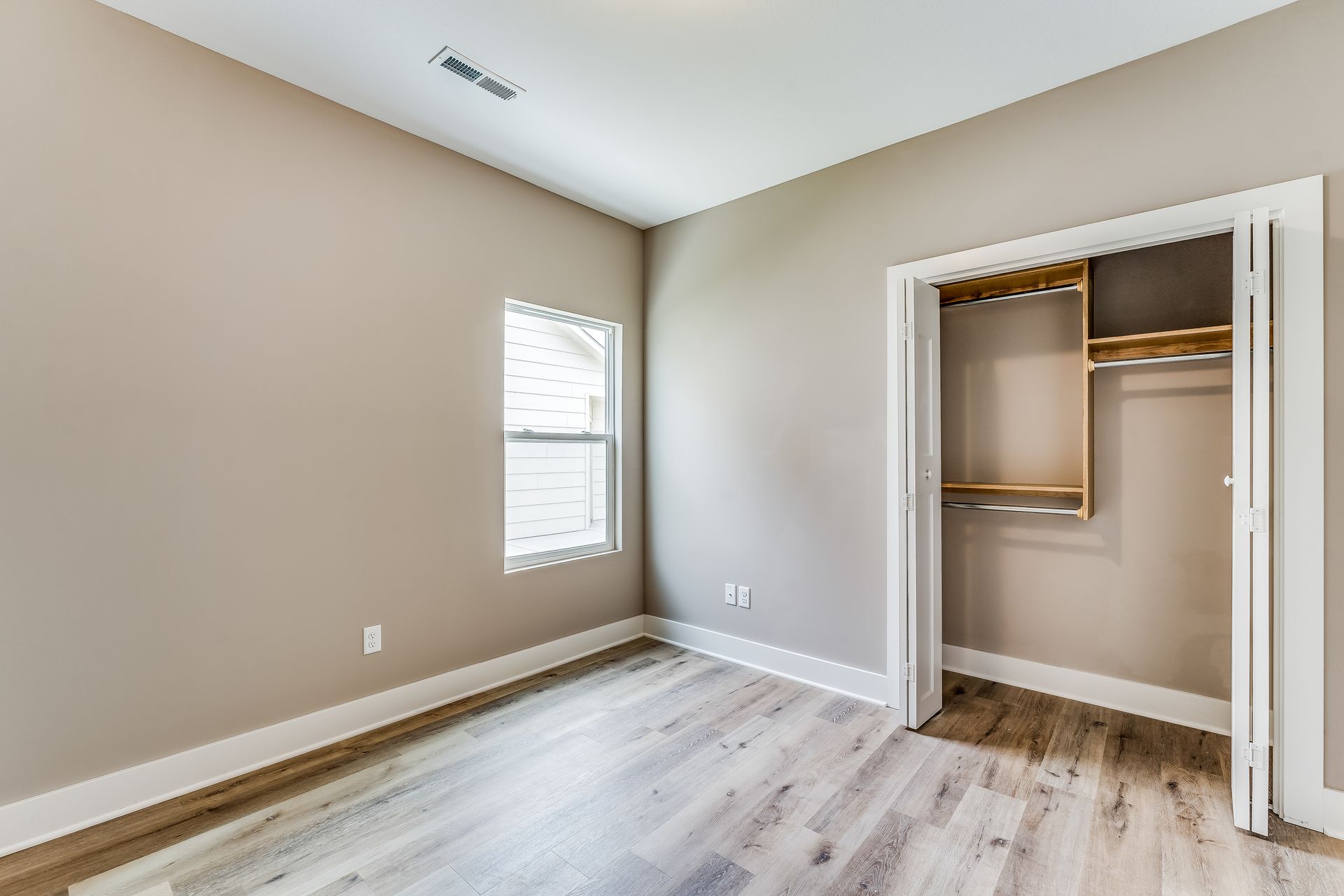 An empty bedroom with hardwood floors and a closet.