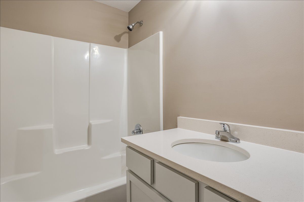 A bathroom with a sink , tub and shower.