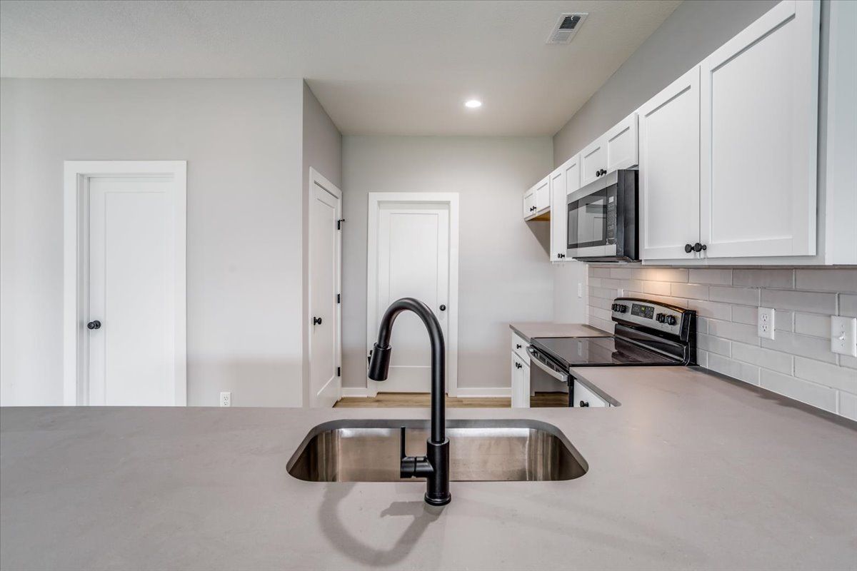 A kitchen with a sink , stove and microwave.