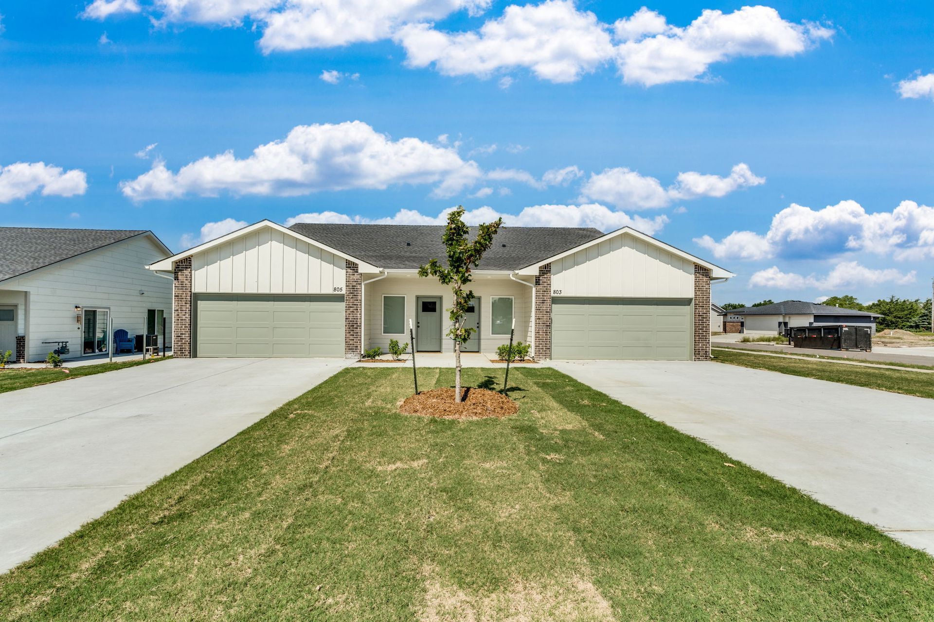 A house with two garages and a tree in front of it.