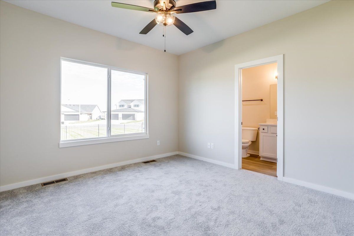 An empty bedroom with a ceiling fan and a toilet.