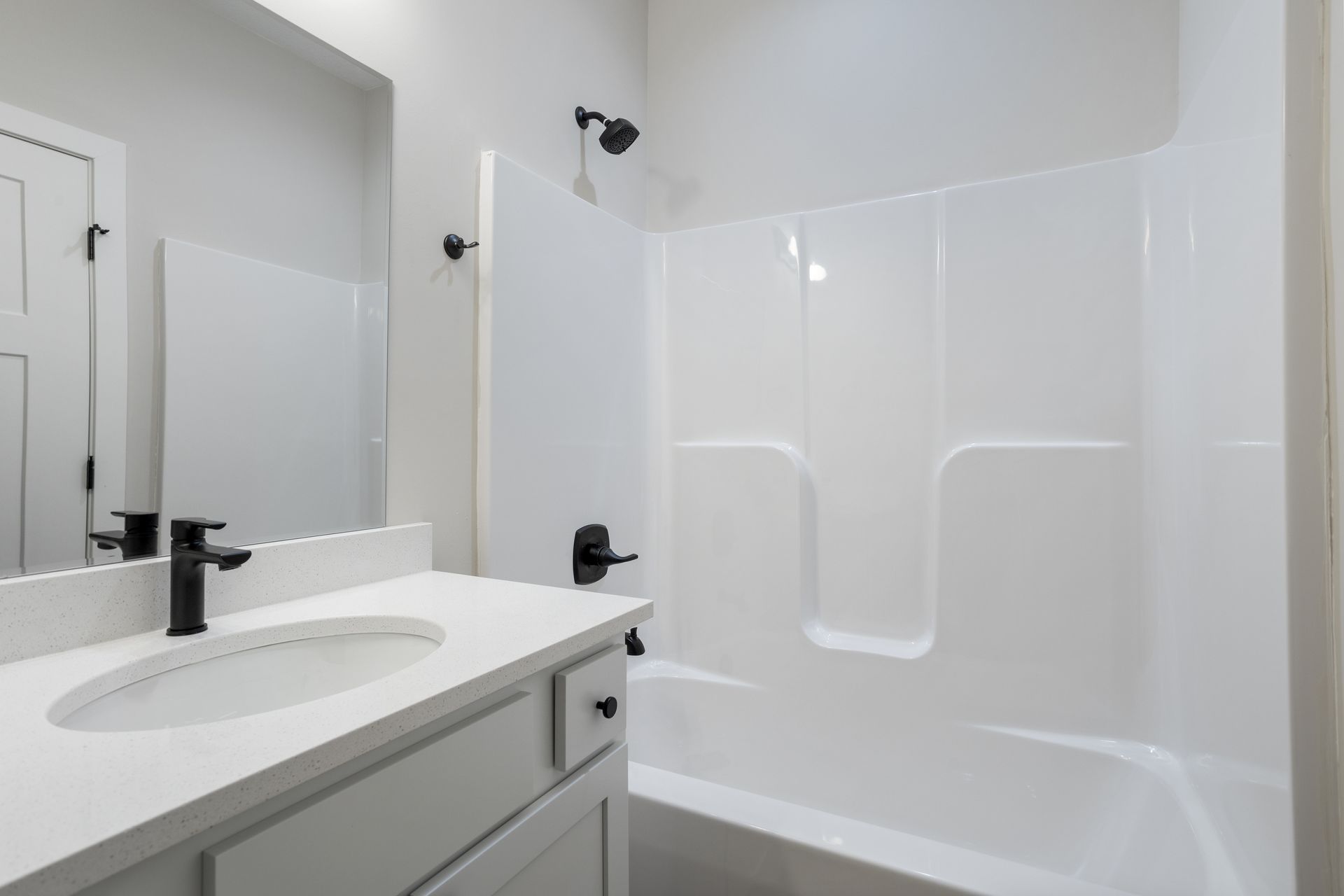 A bathroom with a sink , tub , shower and mirror.