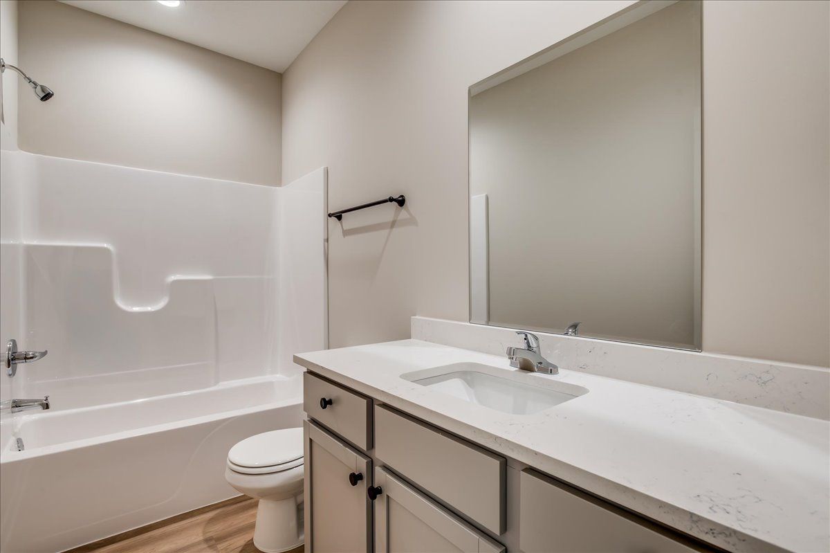 A bathroom with a sink , toilet , shower and mirror.