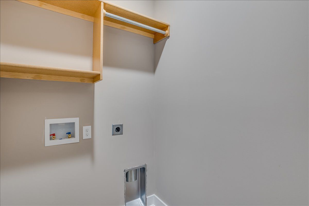 A laundry room with a wooden shelf and a sink.